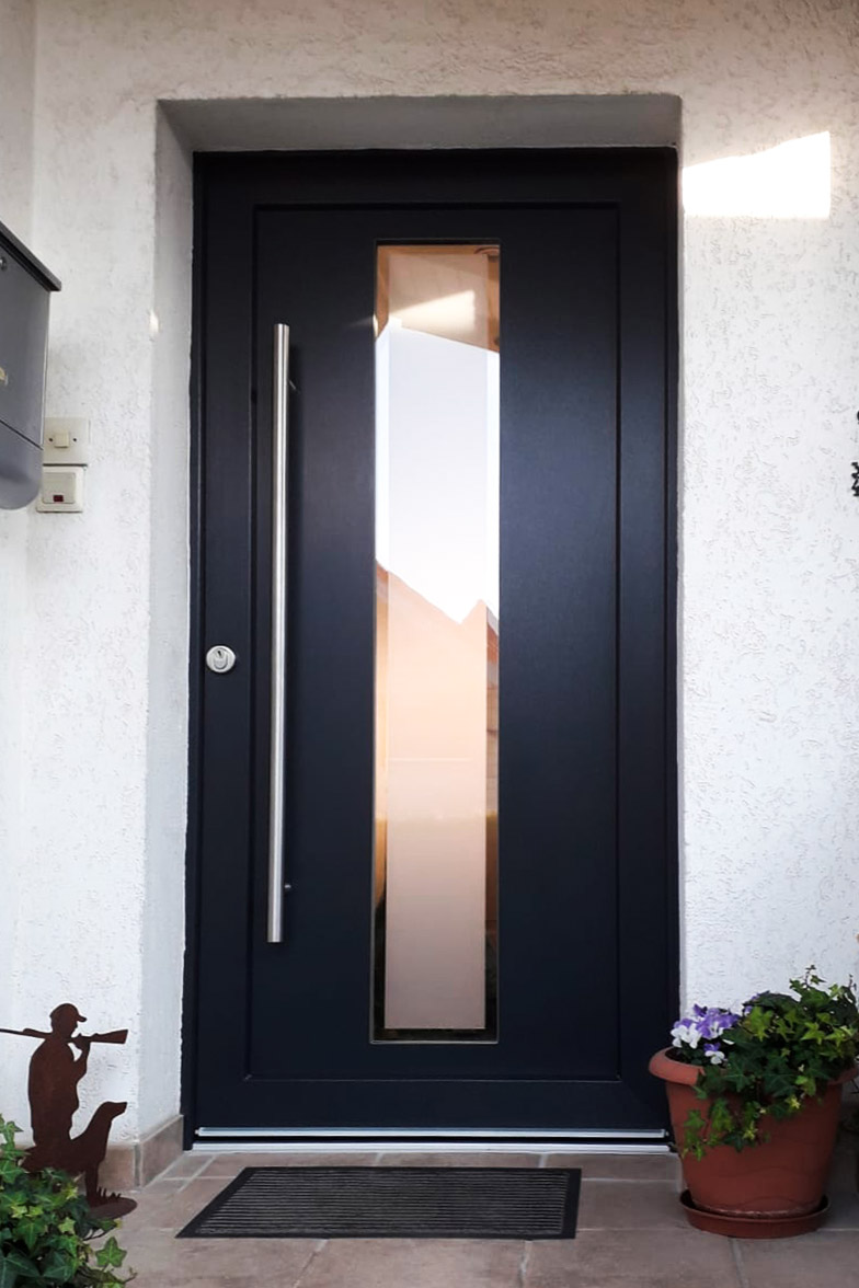 Haustür in Schwarz mit einem schmalen Glasstreifen und langem Griff